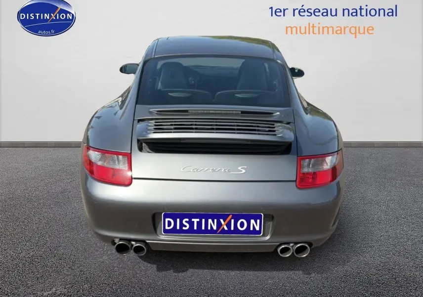 Vue arrière d'une Porsche 911 (997) Carrera S gris métallisé avec double sortie d'échappement et aileron intégré.