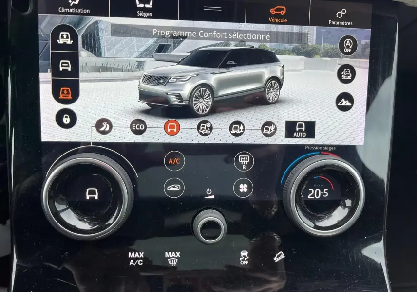 Écran tactile intérieur montrant un Range Rover Velar gris ammonite en vue 3/4 avant avec options de conduite et climatisation.