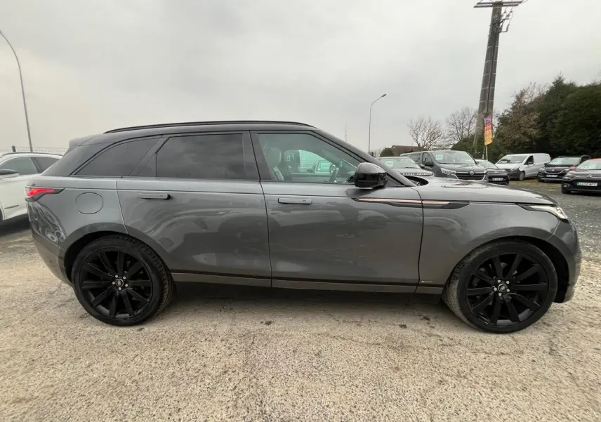 Vue latérale gauche d'un Range Rover Velar gris ammonite avec jantes noires 21 pouces et toit panoramique.