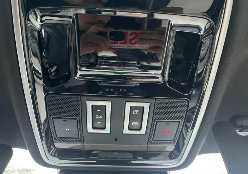 Vue en contre-plongée du panneau de commande du toit ouvrant panoramique du Range Rover Velar gris ammonite, avec boutons et éclairage rouge.