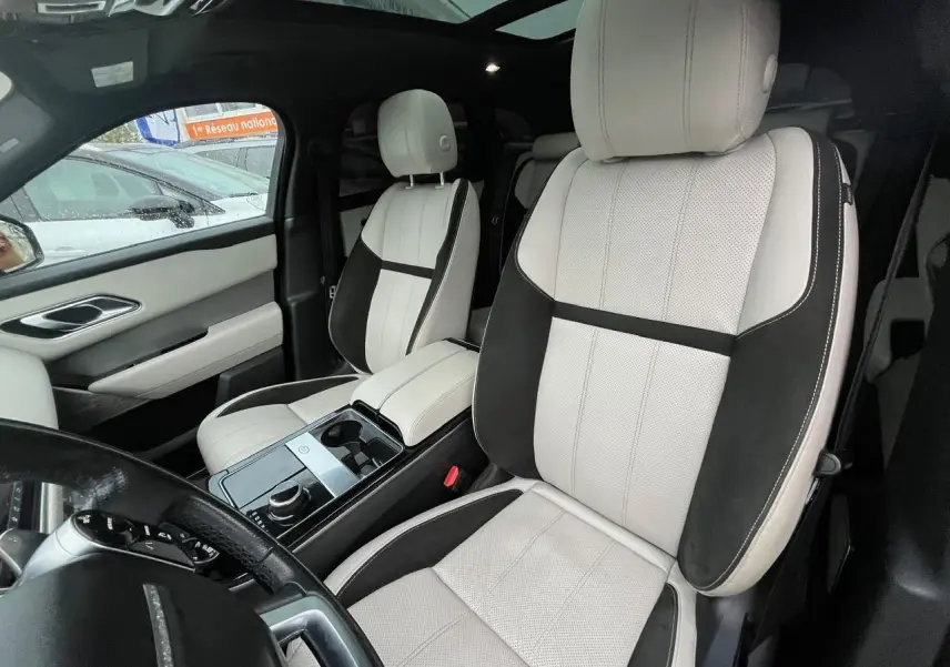 Vue intérieure du Range Rover Velar 2017 montrant les sièges avant bicolores beige et noir avec console centrale brillante.