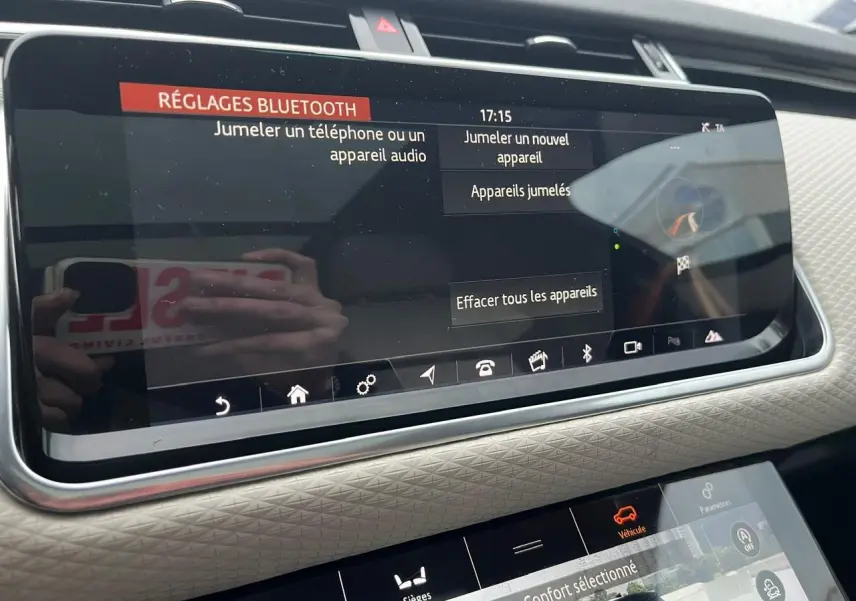 Vue rapprochée de l’écran tactile central du Range Rover Velar gris ammonite, affichant les réglages Bluetooth et options véhicule.