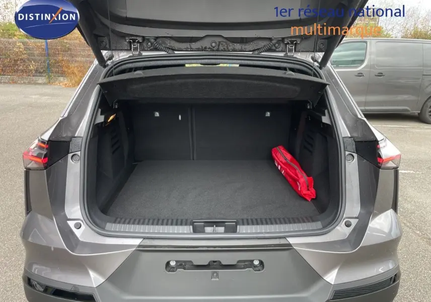 Vue arrière du coffre ouvert d'une Renault Symbioz gris cassiopée métal, avec un kit de sécurité rouge visible à l'intérieur.