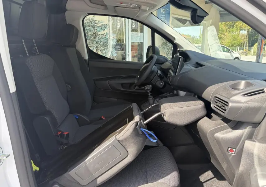 Vue intérieure côté conducteur du Peugeot Partner blanc 2026, montrant les sièges, volant multifonctions et tableau de bord.