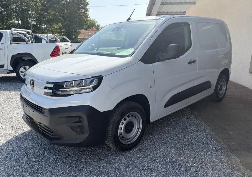 Vue 3/4 avant droit d’un Peugeot Partner blanc 2026, fourgon diesel avec pare-chocs et protections latérales noires.