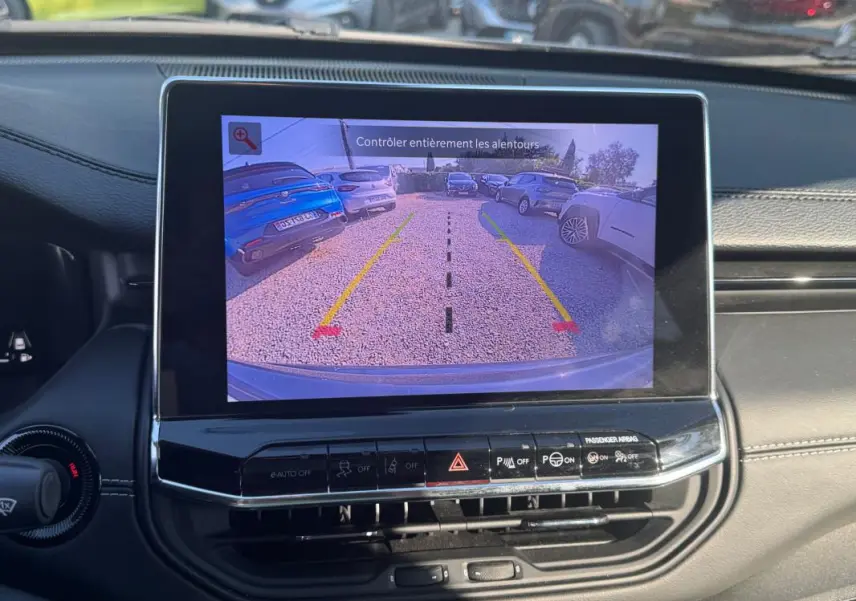 Écran tactile intérieur du Jeep Compass 2025 montrant la caméra de recul avec vue arrière sur un parking.