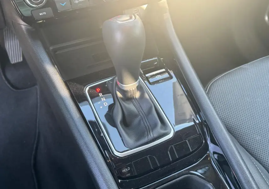 Gros plan sur la console centrale noire du Jeep Compass 2025 avec levier de vitesse automatique et siège gris perforé.
