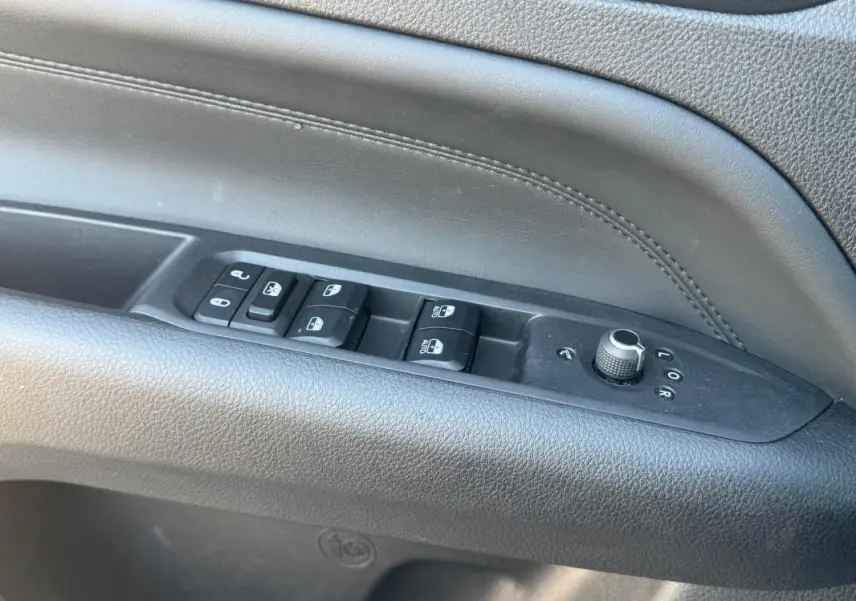 Gros plan sur les commandes de lève-vitres et réglages des rétroviseurs sur la porte intérieure noire du Jeep Compass 2025.