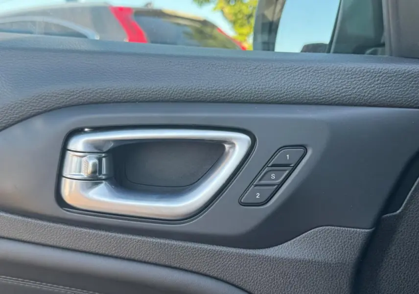 Poignée intérieure de porte côté gauche du Jeep Compass bleu 2025 avec boutons de mémoire des sièges.