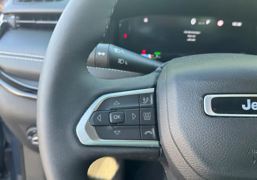 Gros plan sur le volant noir du Jeep Compass 2025, avec commandes intégrées et logo Jeep visible au centre.