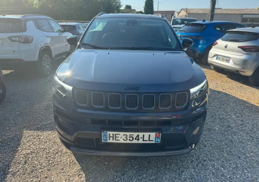 Vue avant d'un Jeep Compass bleu 2025 avec calandre caractéristique et barres de toit visibles en extérieur.