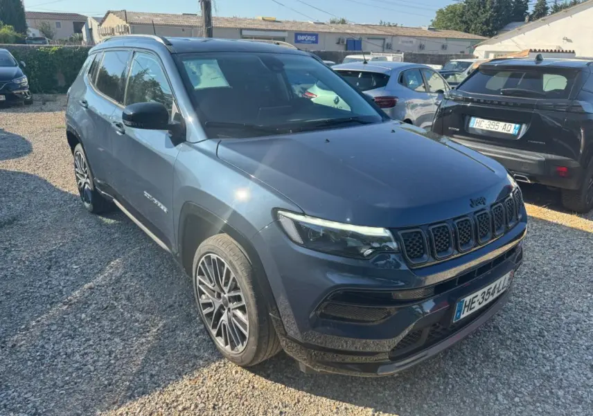 Jeep Compass bleu vue 3/4 avant droit, avec jantes alliage 19 pouces et barres de toit visibles.