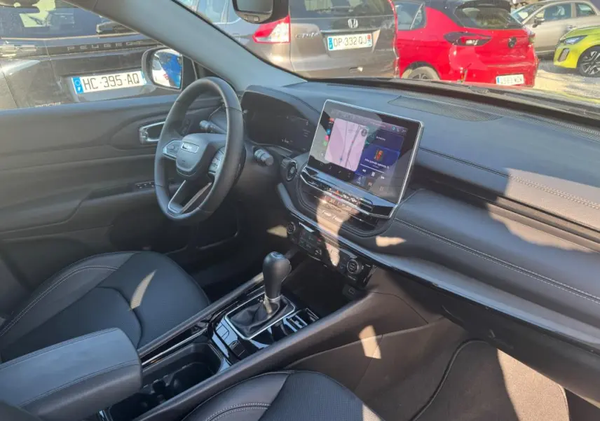 Intérieur avant droit du Jeep Compass bleu 2025, montrant tableau de bord moderne et écran tactile central.