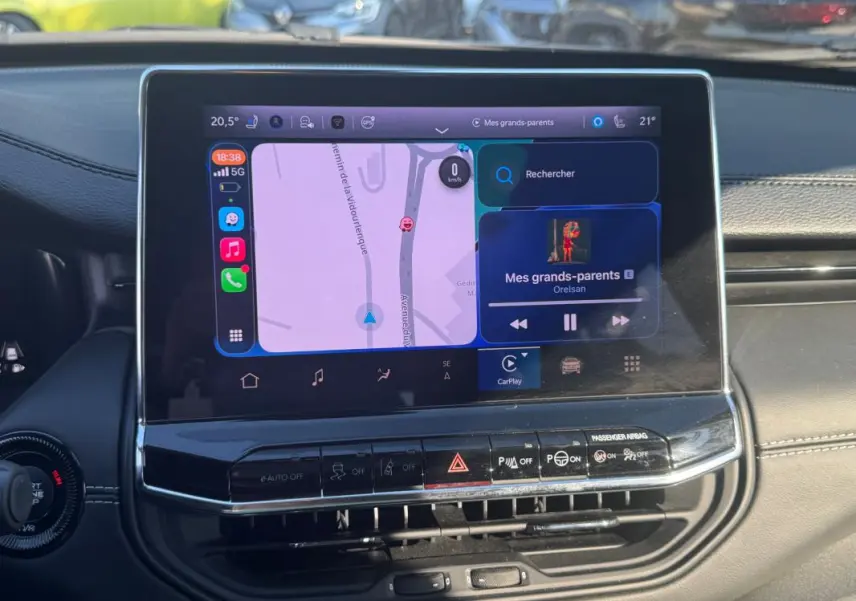 Écran tactile central du Jeep Compass 2025 montrant la navigation et la musique, avec tableau de bord noir en arrière-plan.
