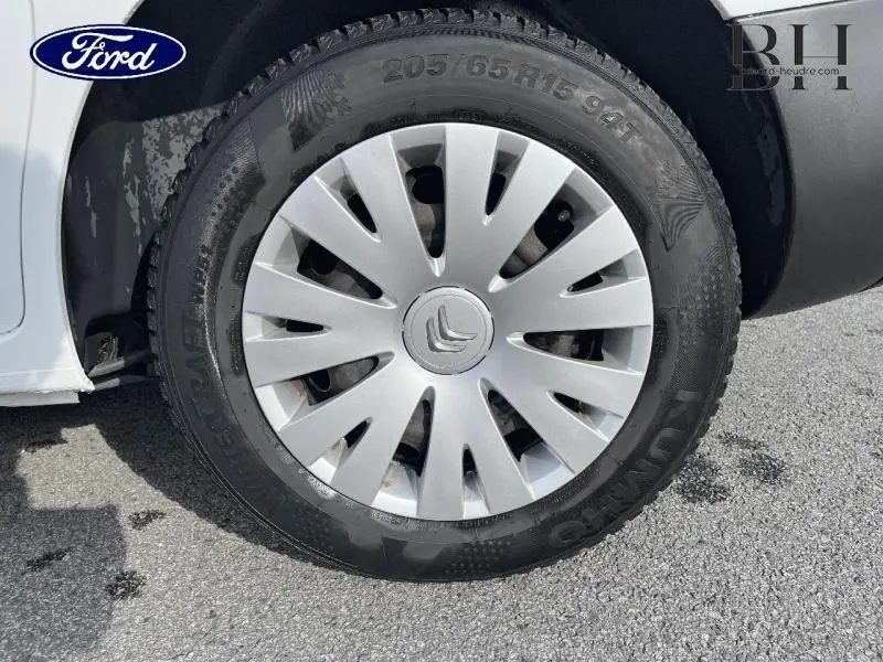 Gros plan sur la roue avant gauche blanche Banquise d'un Citroën Berlingo avec enjoliveur argenté et logo Citroën central.