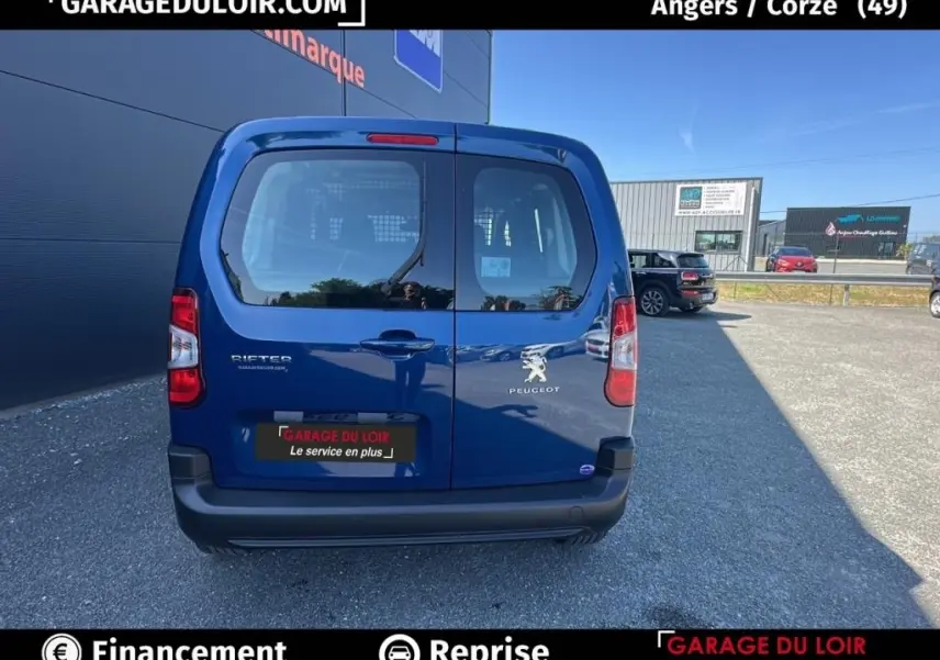 Vue arrière du Peugeot Rifter bleu 2024 avec portes battantes et logo visible sur un parking extérieur.