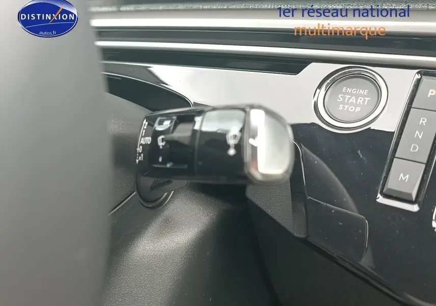Gros plan sur la commande de phares et le bouton start/stop du tableau de bord noir brillant du Peugeot 3008 gris Artense.