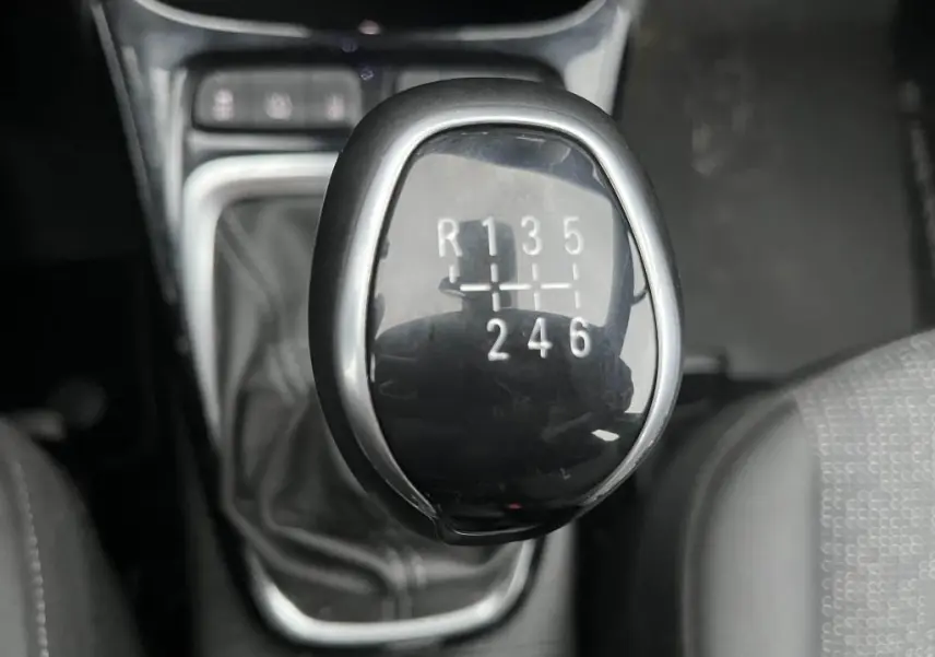 Gros plan sur le levier de vitesses manuel noir brillant de l'Opel Crossland X 1.2i Turbo, intérieur sombre.