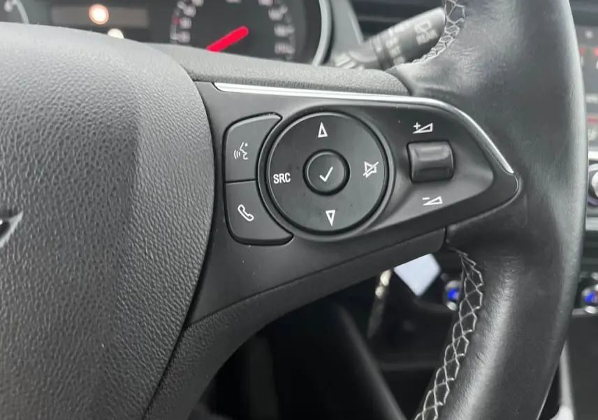 Gros plan sur les commandes au volant en cuir noir de l'Opel Crossland X 2021, avec boutons multifonctions visibles.