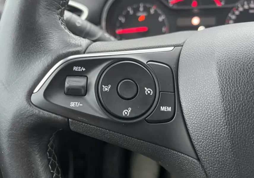 Gros plan sur les commandes de régulateur de vitesse au volant noir de l'Opel Crossland X 2021.