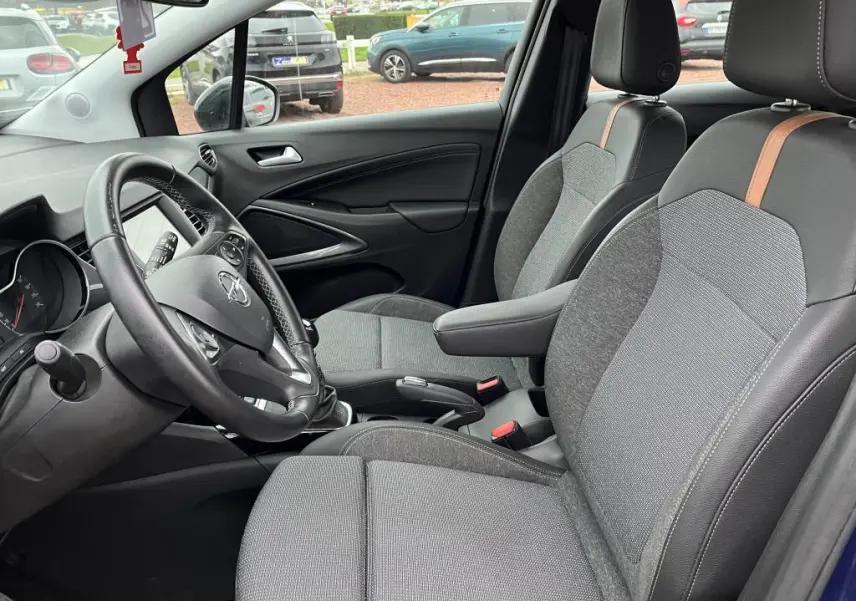 Vue intérieure côté conducteur de l’Opel Crossland X bleu clair 2021, sièges gris avec surpiqûres marron et volant multifonction.