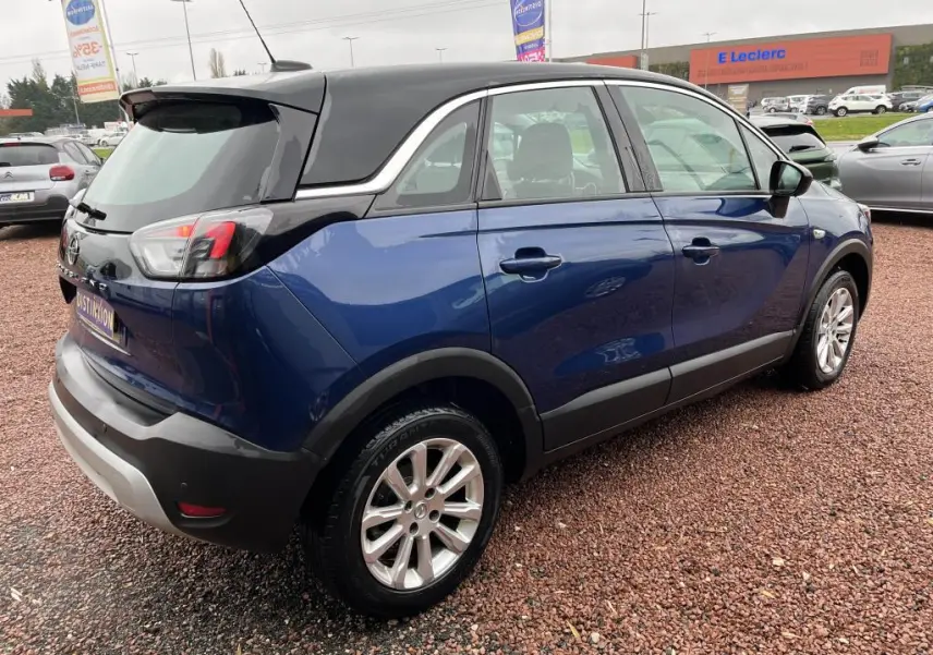 Opel Crossland X bleu clair vue 3/4 arrière droit avec toit noir et jantes alliage sur parking extérieur.