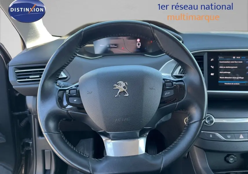 Vue intérieure centrée sur le volant cuir noir de la Peugeot 308 Business 2020 avec tableau de bord digital et écran tactile.