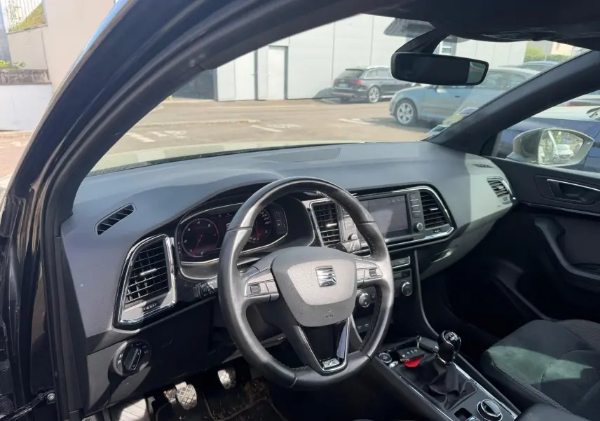 Vue intérieure côté conducteur du SEAT Ateca noir 2019, volant cuir multifonctions et tableau de bord moderne.