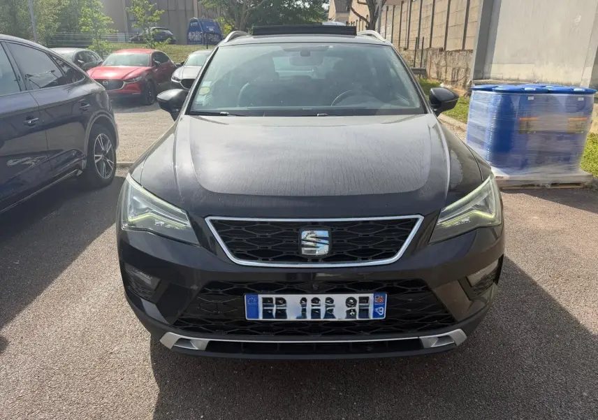 Vue avant d'un SEAT Ateca noir 2019 avec calandre chromée et phares LED allumés, stationné en extérieur.