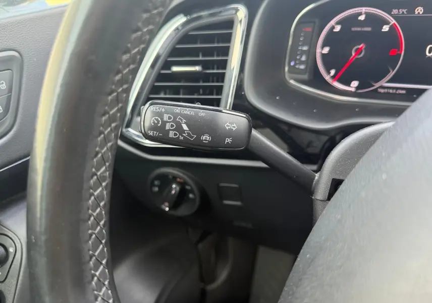 Gros plan sur la manette de régulateur de vitesse à gauche du volant cuir noir du tableau de bord digital du SEAT Ateca noir.