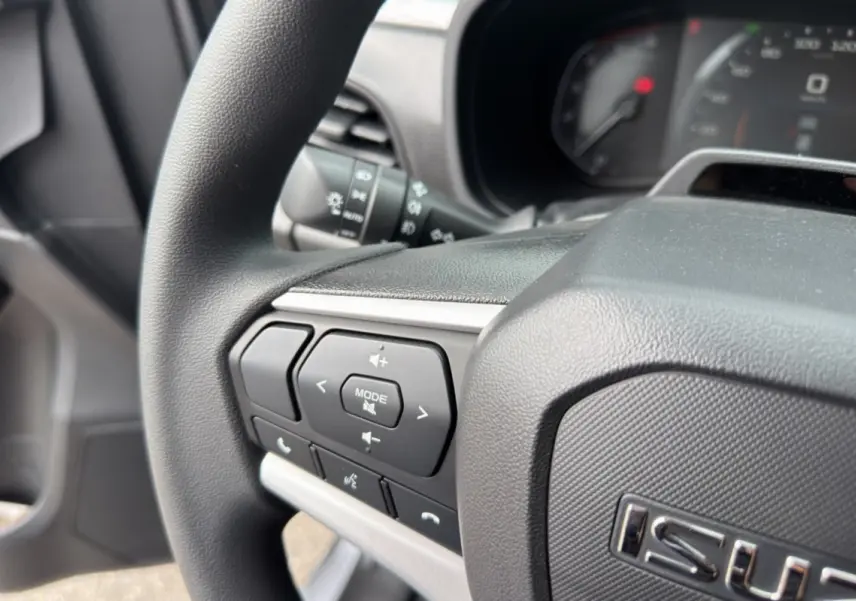 Gros plan sur le volant multifonctions noir de l'Isuzu D-MAX 2026 avec commandes audio et téléphone intégrées.