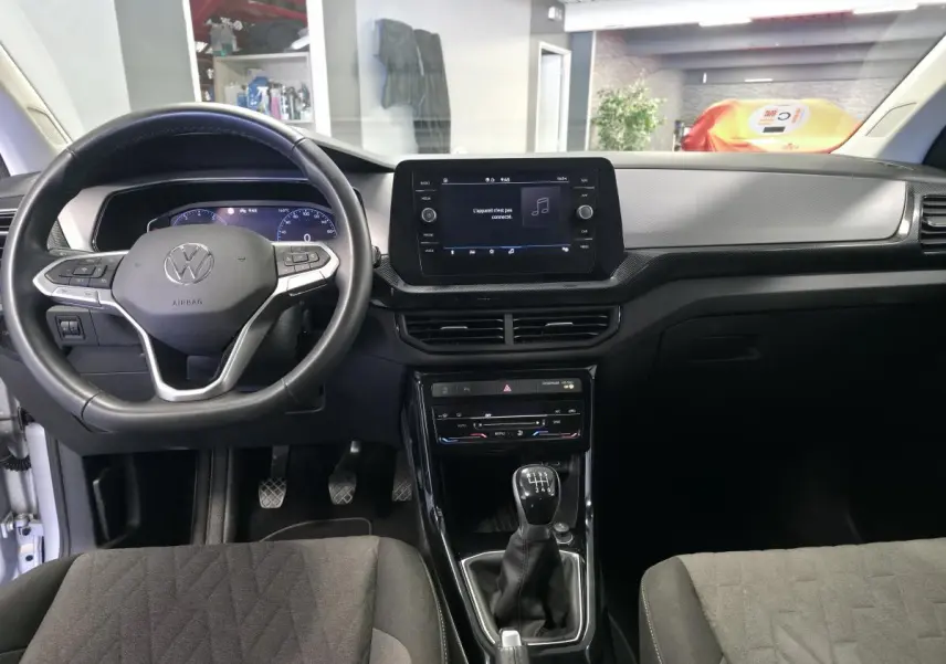 Vue intérieure frontale du Volkswagen T-Cross gris, avec volant multifonction en cuir et écran tactile central.