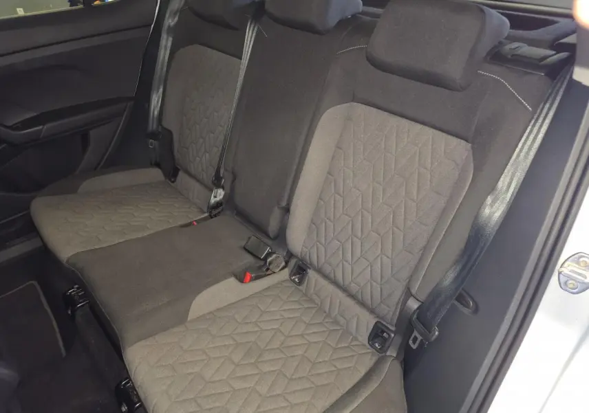 Vue intérieure de la banquette arrière en tissu gris foncé du Volkswagen T-Cross 2025, avec ceintures de sécurité visibles.