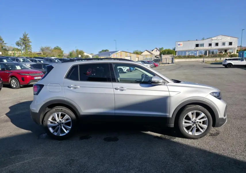 Vue de profil côté gauche d'un Volkswagen T-Cross gris métallisé avec jantes alliage 17 pouces sur parking.