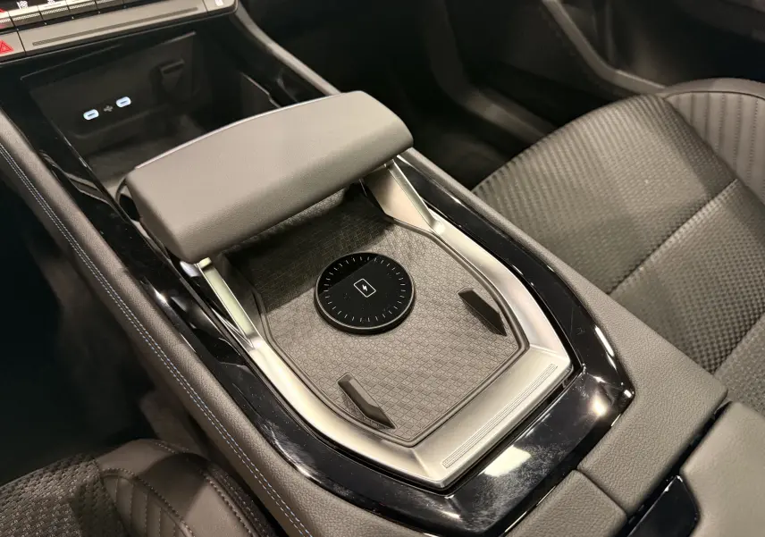 Gros plan sur la console centrale noire et grise du Renault Austral 2026 avec repose-bras et zone de charge sans fil.