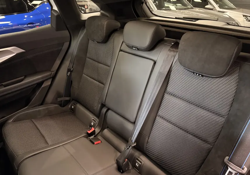 Vue intérieure des sièges arrière noirs en cuir et tissu du Renault Austral Full hybrid, avec ceinture de sécurité visible.