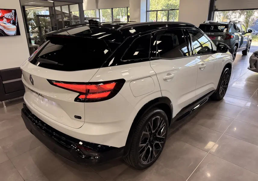 Vue 3/4 arrière droite du Renault Austral blanc nacré avec toit noir et jantes noires en concession.