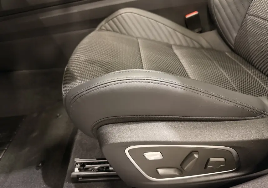 Gros plan sur le siège avant droit en cuir noir du Renault Austral Full hybrid, avec commandes électriques visibles.
