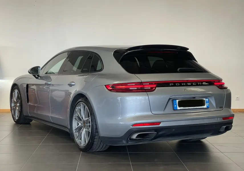 Vue 3/4 arrière droite d'une Porsche Panamera Sport Turismo gris métallisé avec feux arrière connectés et jantes alliage.