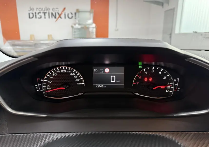 Vue rapprochée du tableau de bord numérique de la Peugeot 208 1.2i PureTech 100, affichant 42103 km et vitesse à 0 km/h.