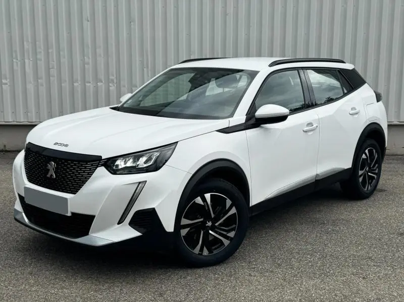 Peugeot 2008 blanc banquise vue 3/4 avant droit, avec jantes alliage et barres de toit noires.