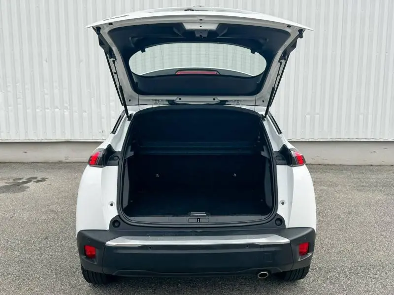 Vue arrière du Peugeot 2008 blanc banquise avec coffre ouvert montrant l'espace de chargement vide.