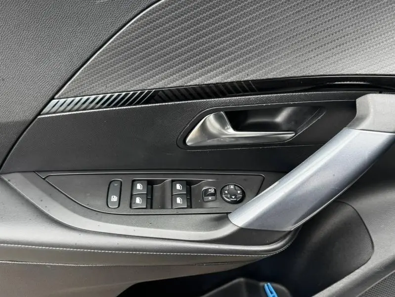 Gros plan sur la porte côté gauche intérieure du Peugeot 2008 blanc banquise, avec commandes de vitres et poignée argentée.