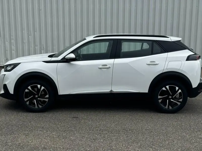 Profil côté gauche du Peugeot 2008 blanc banquise avec toit noir et jantes alliage distinctives.