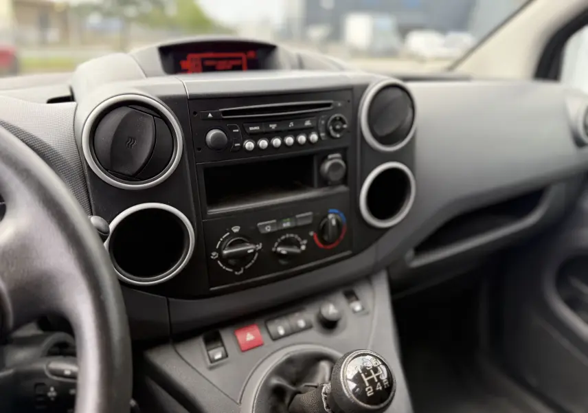 Vue rapprochée de l’intérieur du Peugeot Partner 2017, montrant la console centrale noire avec la radio et le levier de vitesse manuel.