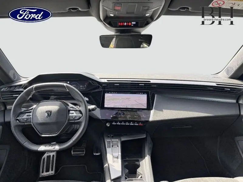Intérieur moderne de Peugeot 308 SW PHEV blanc, vue frontale du tableau de bord avec écran tactile et volant multifonction.