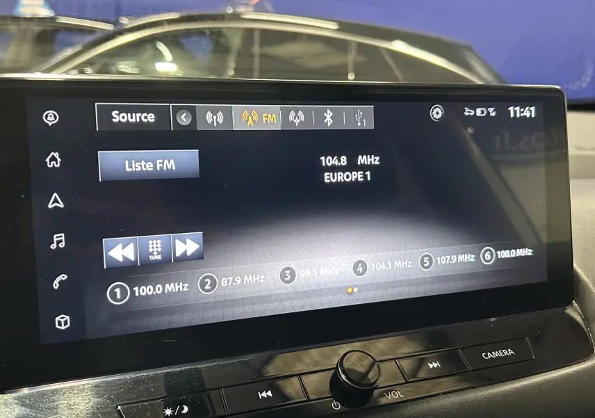 Écran tactile multimédia du Nissan Qashqai blanc lunaire, affichant la radio FM avec station Europe 1 à 104,8 MHz.