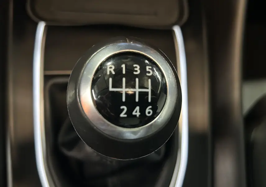 Gros plan sur le levier de vitesse manuel du Nissan Qashqai blanc lunaire, montrant les six rapports et la marche arrière.