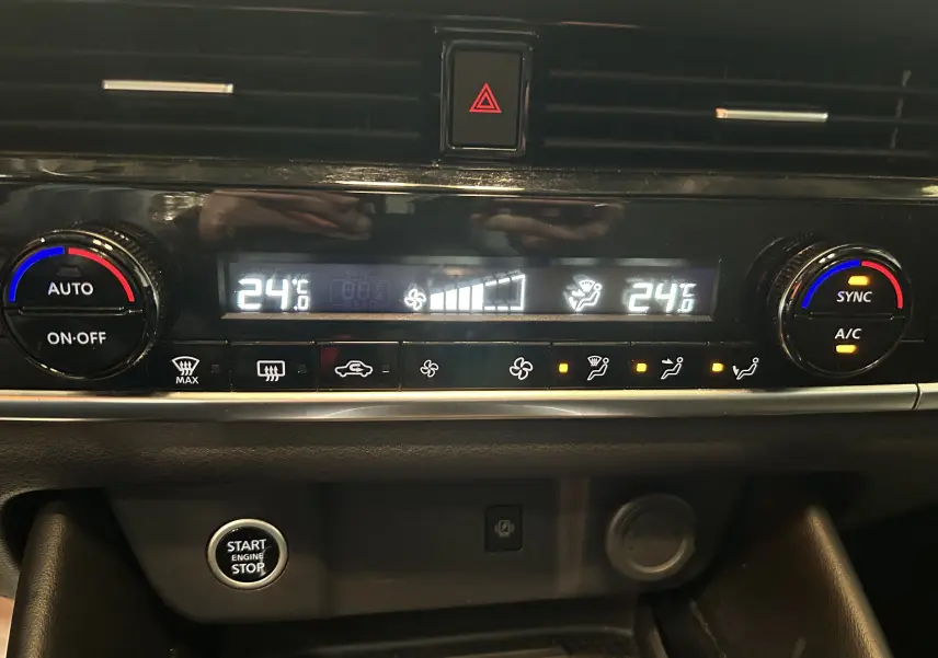 Gros plan sur la console centrale du Nissan Qashqai blanc lunaire, affichant la climatisation à 24°C avec commandes digitales.