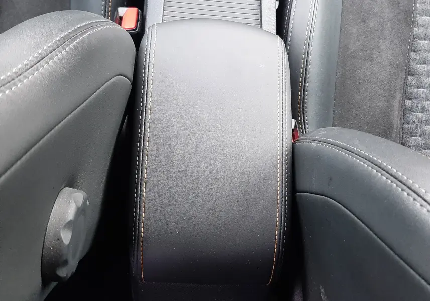 Vue plongeante sur l'accoudoir central noir avec surpiqûres contrastantes dans l'habitacle d'une Peugeot 308 SW 2021.